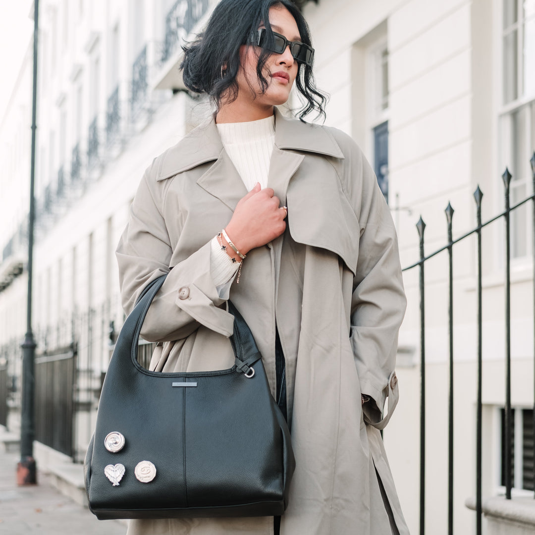 Woman in a trench coat holding a blue handbag on a city street.